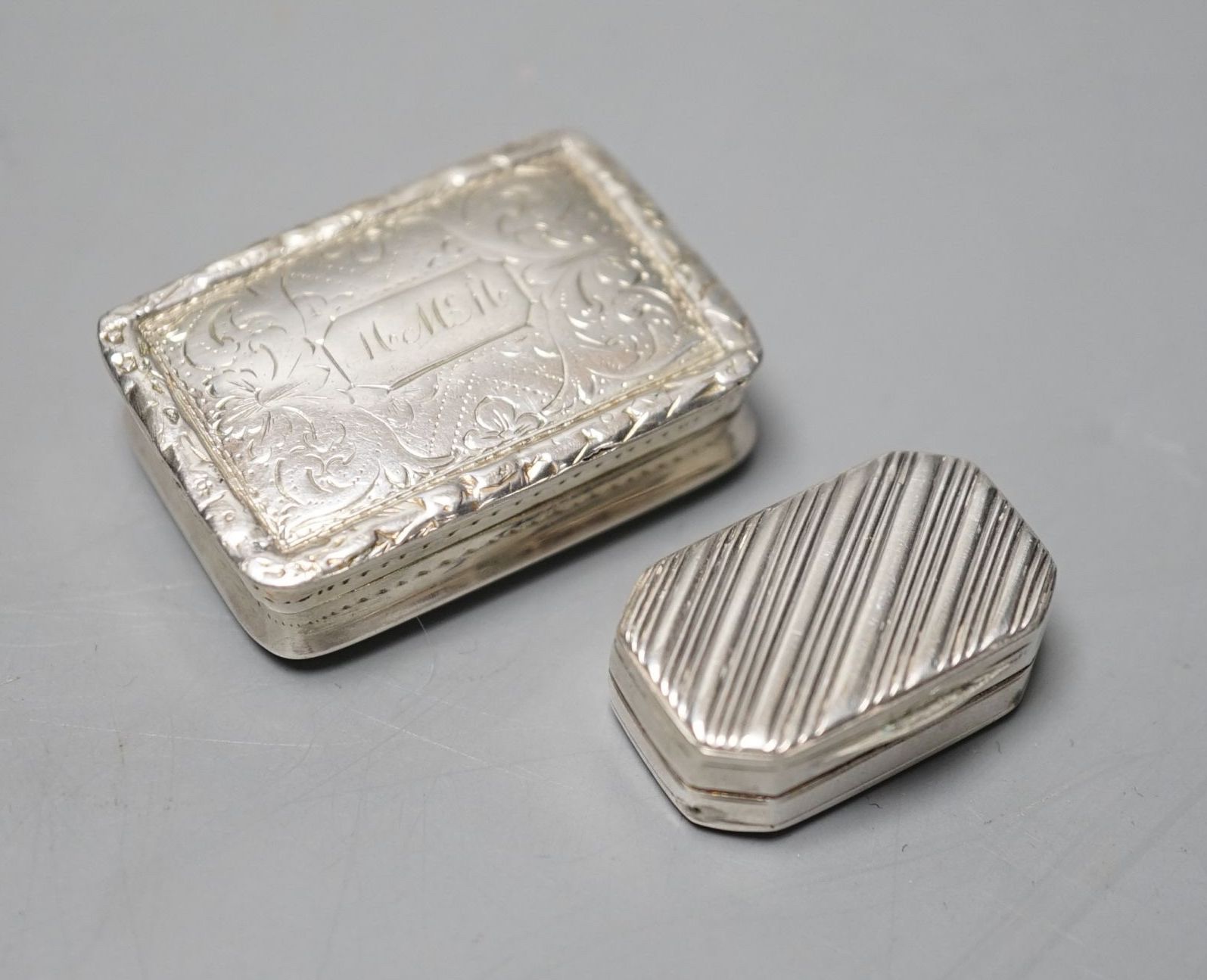 A William IV silver rectangular vinaigrette by Nathaniel Mills, Birmingham, 1836, with engraved decoration and initials, 35mm and one other earlier smaller vinaigrette, maker W?, London, 1813, 12mm.